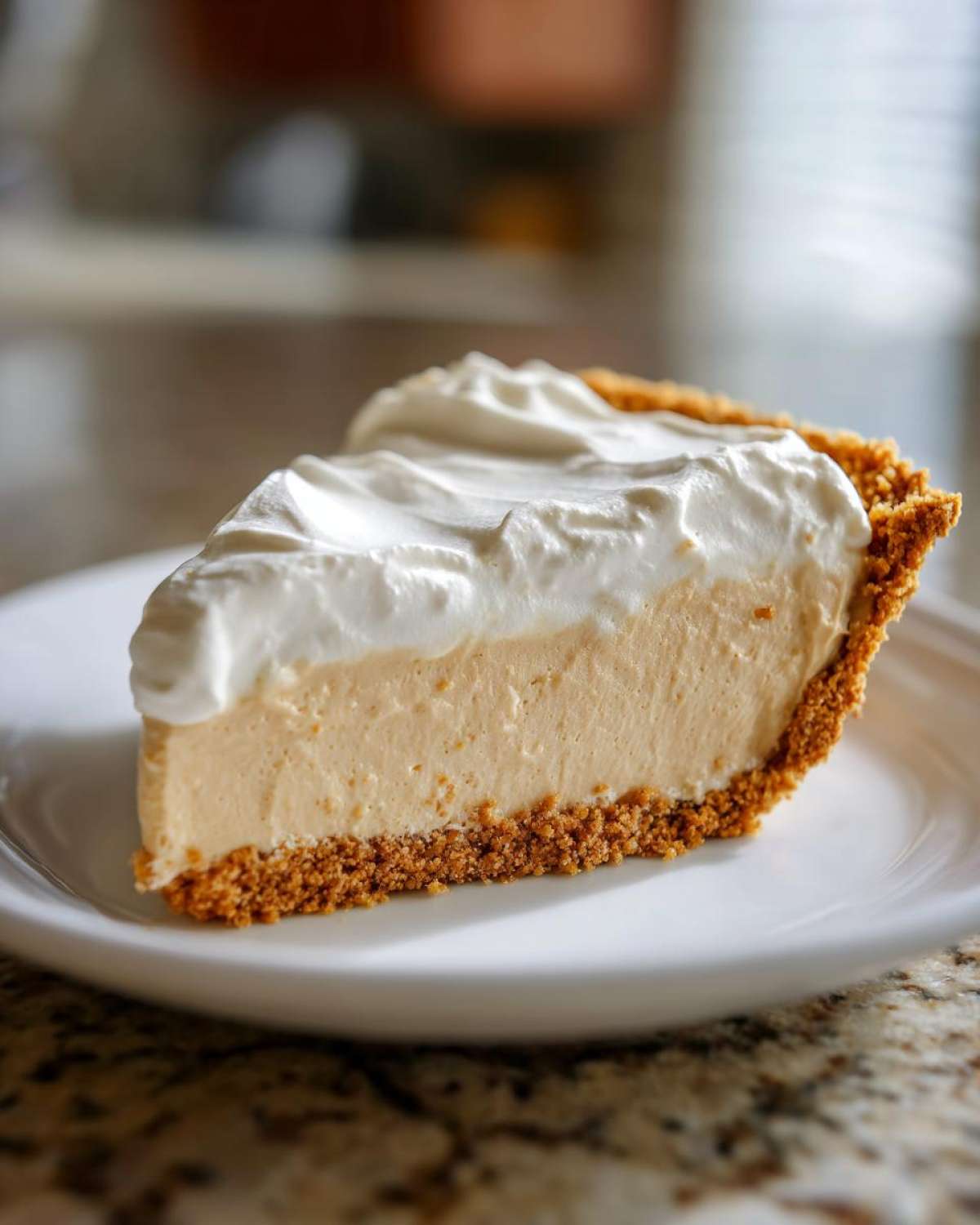 A perfect slice of creamy peanut butter pie with a graham cracker crust and whipped topping.