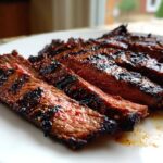 Close-up of perfectly grilled and sliced carne asada, showing a medium-rare center and dark char marks from the carne asada marinade.