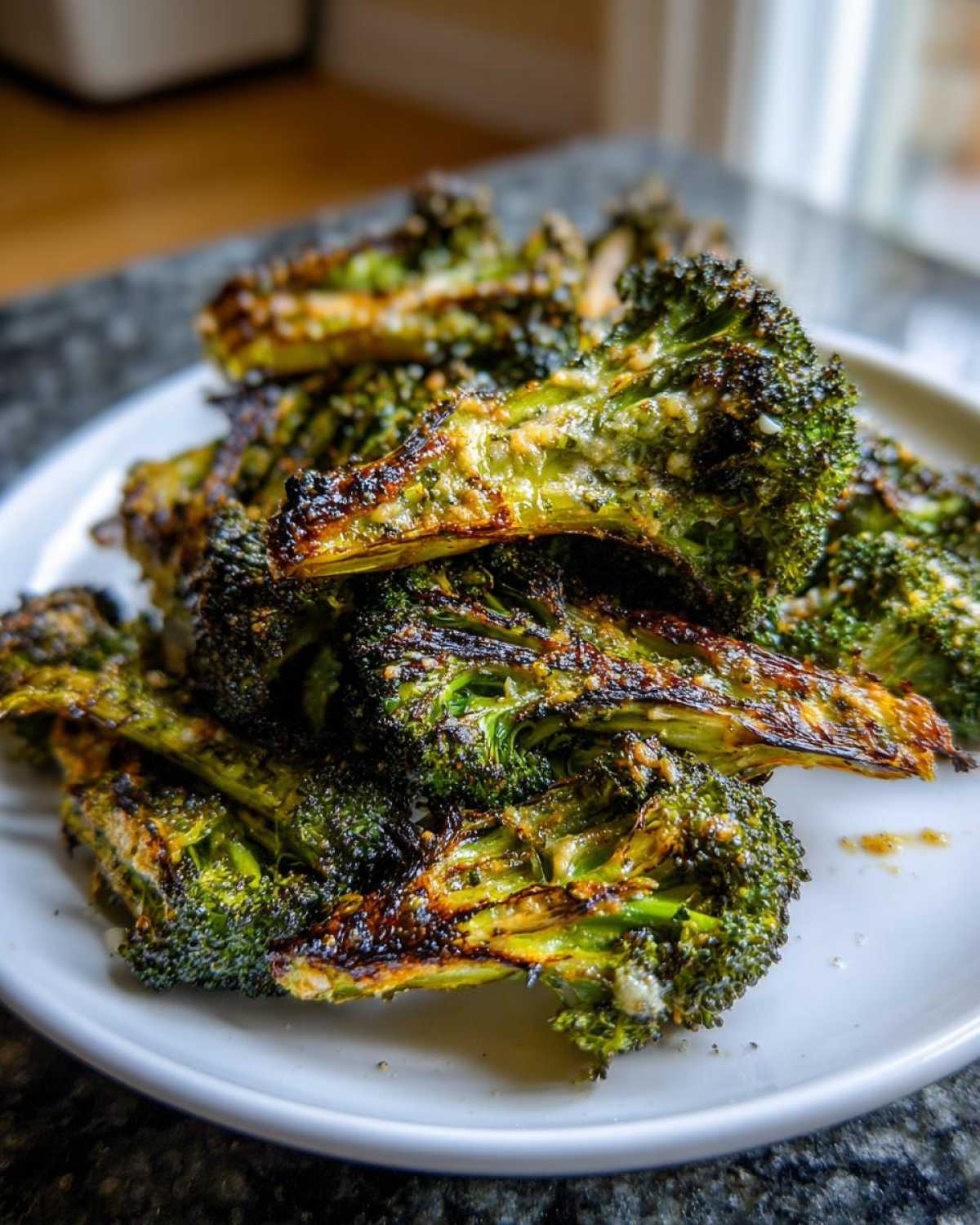 Close-up of crispy, charred, and seasoned smashed broccoli piled high on a white plate.