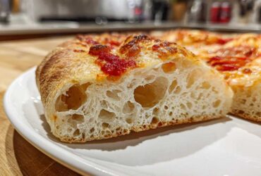 Close-up of a slice showing the airy, open crumb structure of sourdough discard pizza dough with tomato sauce.