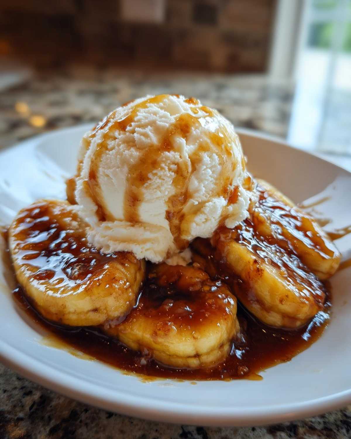 Close-up of warm, caramelized bananas in rich sauce, topped with vanilla ice cream, ready to eat Bananas Foster.
