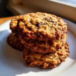 A close-up stack of three golden brown, chewy oatmeal cookie treats with visible chocolate chunks.