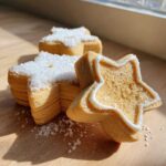 Close-up of soft, star-shaped vegan sugar cookies decorated with white icing and coarse sugar.