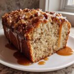 A slice of moist Sweet Alabama Pecan Bread topped with a thick, dripping caramel glaze and pecans.