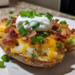 A fully loaded Air Fryer Crispy Potato Skins half topped with melted cheese, bacon bits, sour cream, and chives.