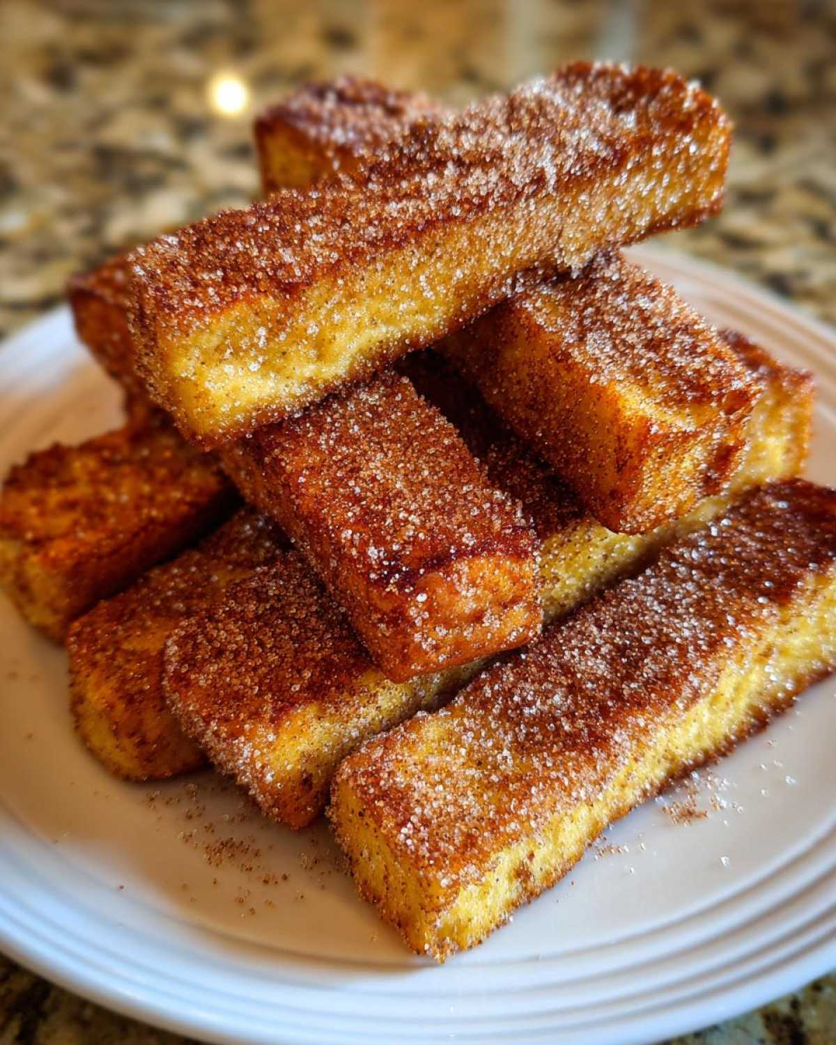 A stack of golden Air Fryer French Toast Sticks generously coated in sparkling cinnamon sugar.
