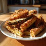 A pile of golden, crispy Air Fryer Zucchini Fries with Parmesan served on a white plate.