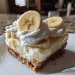 A single serving slice of Banana Pudding Cheesecake Bars topped with whipped cream and fresh banana slices.