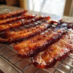 Close-up of shiny, caramelized Brown Sugar Glazed Bacon strips resting on a wire cooling rack.