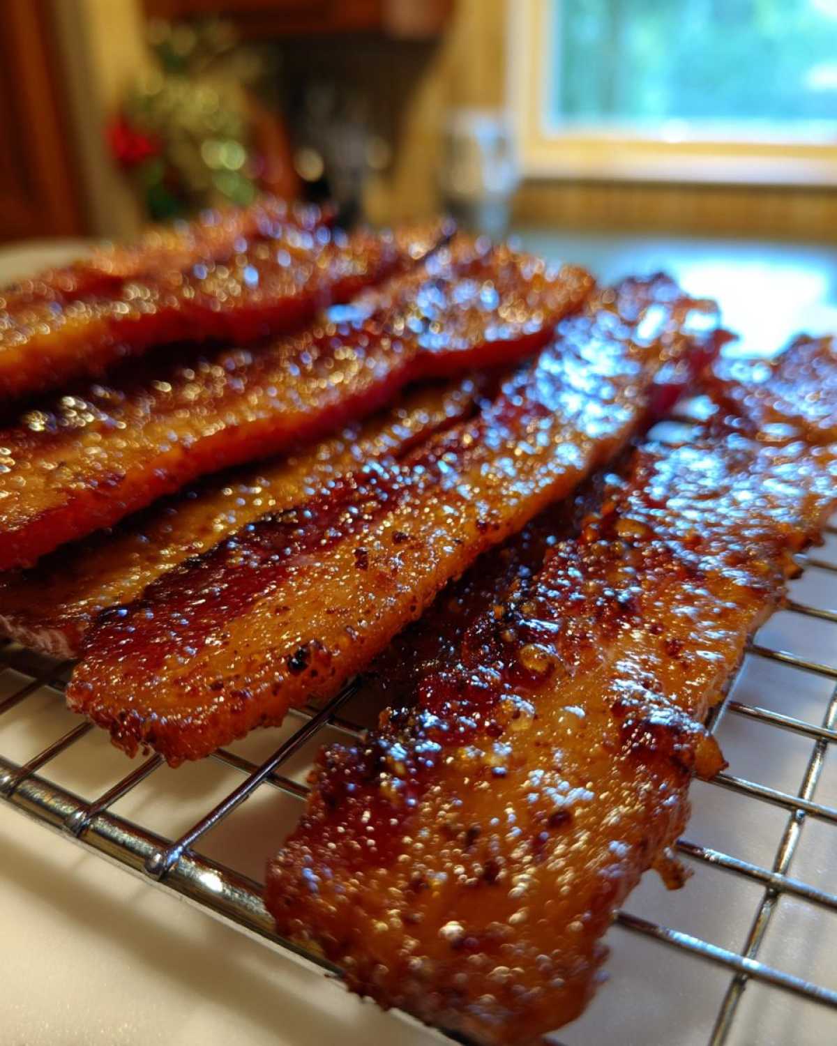Several strips of glistening Brown Sugar Glazed Bacon resting on a wire cooling rack.