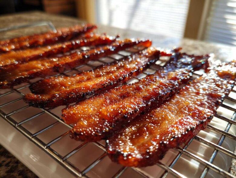Close-up of shiny, caramelized Brown Sugar Glazed Bacon strips resting on a wire cooling rack.