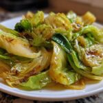 A close-up of glossy, wilted cabbage wedges coated in a savory sauce, ready to serve as Cabbage Stir Fry with Garlic Ginger Sauce.