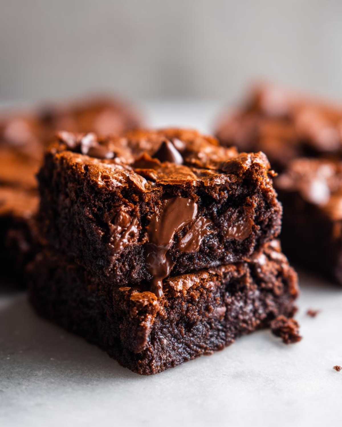 Two stacked, fudgy squares of Chewy Chocolate Chip Cookie Bars with melted chocolate oozing out.
