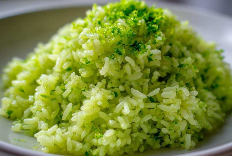 Close-up of bright green Cilantro Lime Rice mounded on a white plate, topped with fresh lime zest.