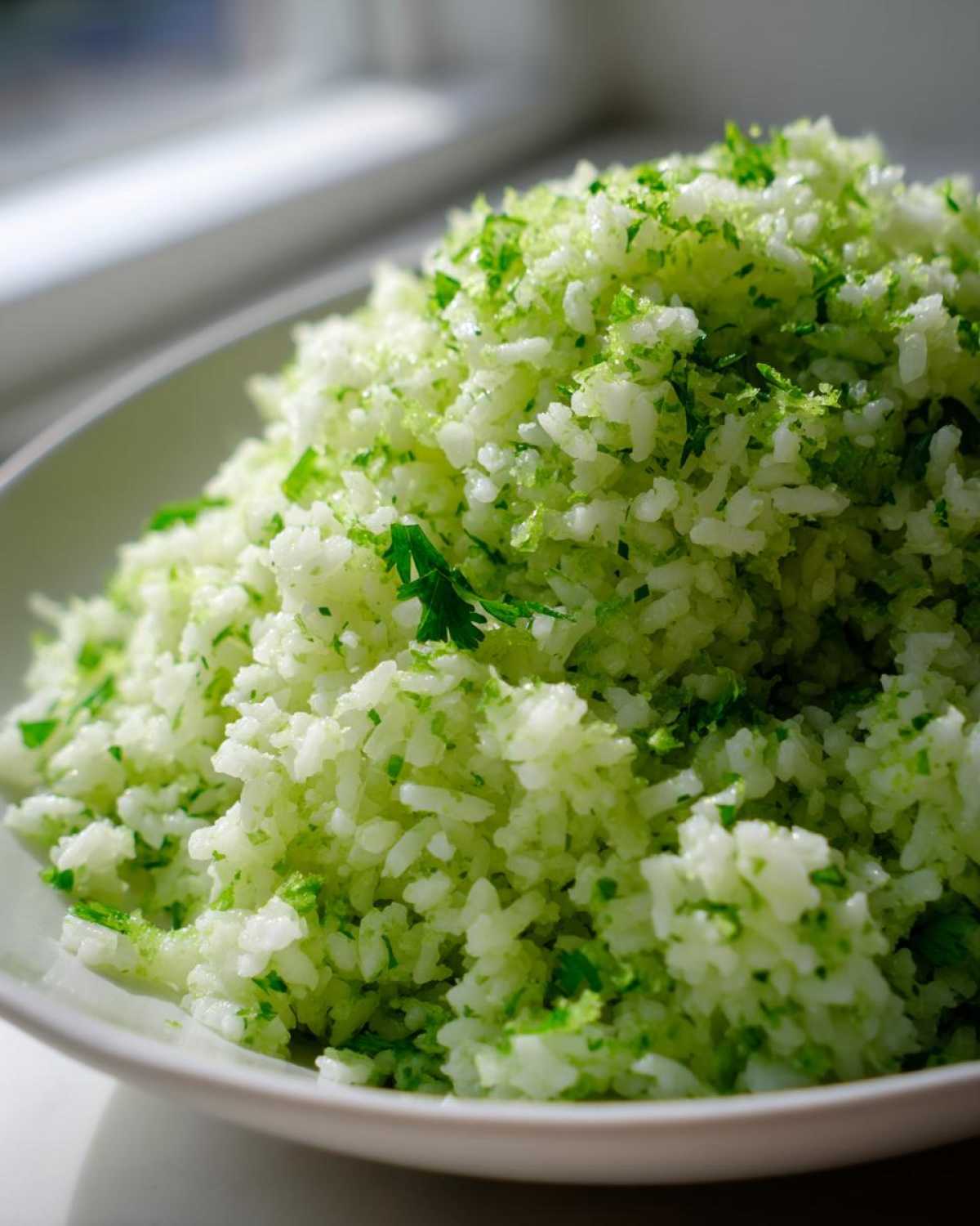 A close-up of fluffy white rice mixed with bright green cilantro and lime zest, perfect for Cilantro Lime Rice for Burrito Bowls.