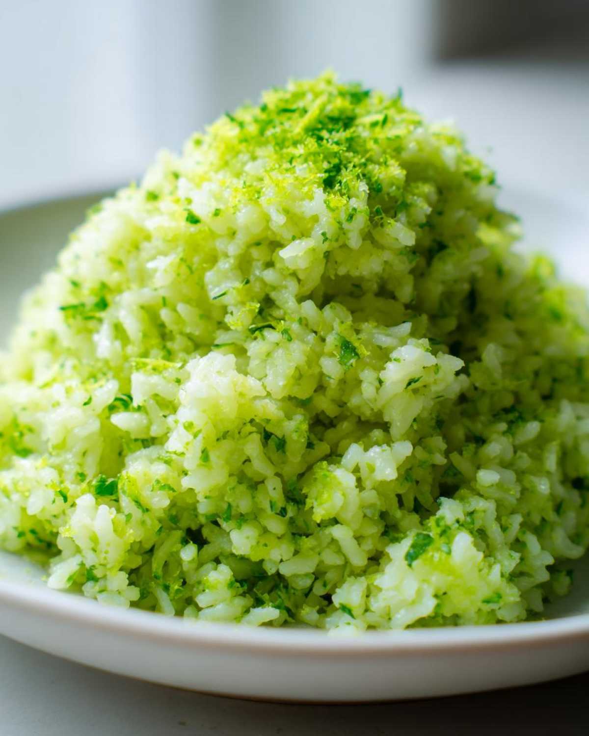 A mound of fluffy white rice mixed with bright green cilantro and lime zest, perfect Cilantro Lime Rice for Burrito Bowls.