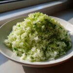 A white bowl filled with fluffy Cilantro Lime Rice, heavily topped with bright green lime zest.