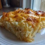 A square slice of golden-brown Copycat Cracker Barrel Hashbrown Casserole with melted, bubbly cheese on top.