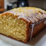Close-up of a freshly baked Copycat Starbucks Iced Lemon Loaf with thick white glaze and lemon zest.