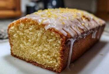 Close-up of a freshly baked Copycat Starbucks Iced Lemon Loaf with thick white glaze and lemon zest.