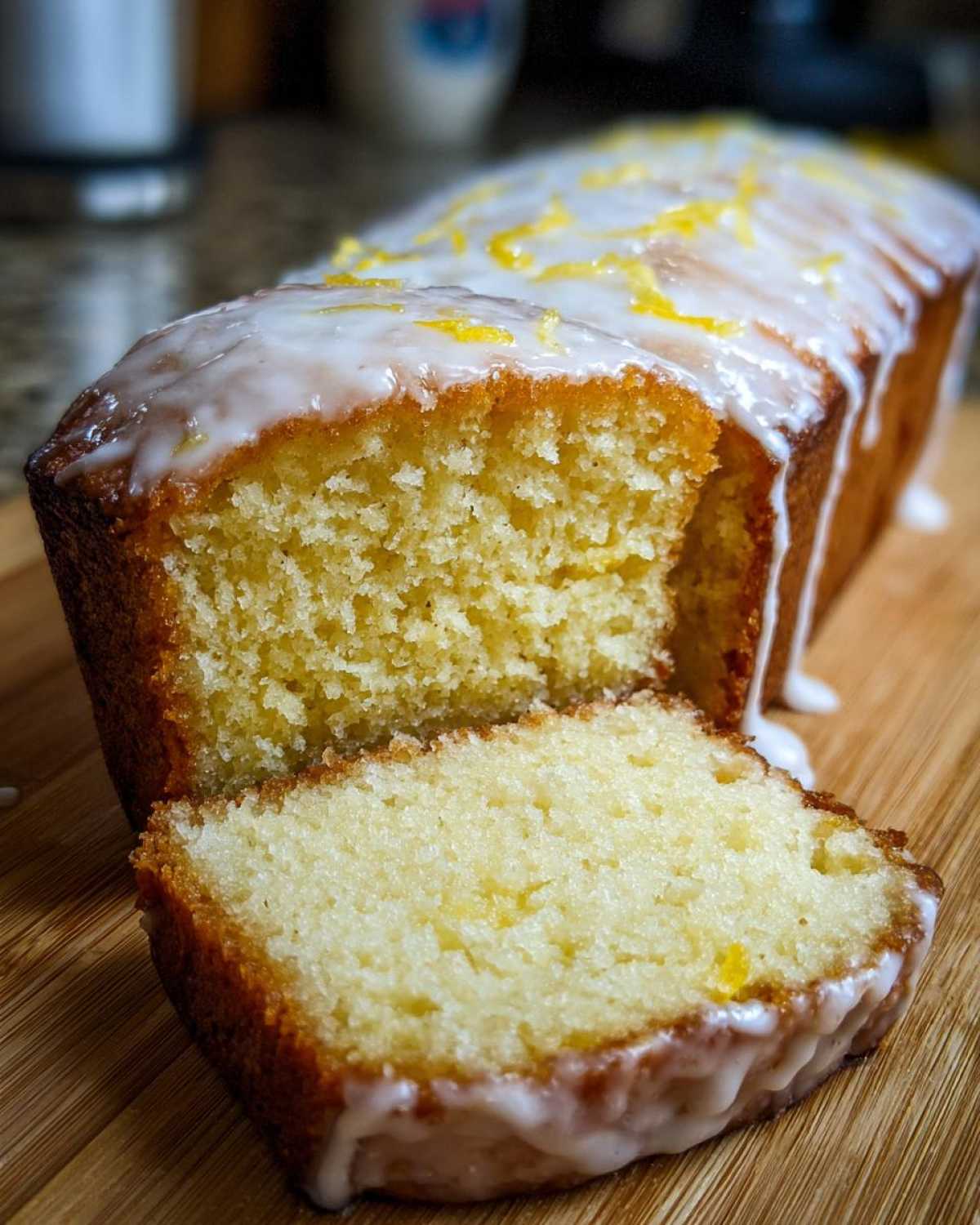 A slice cut from a Copycat Starbucks Iced Lemon Loaf showing the moist crumb and thick lemon glaze.