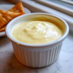 Close-up of creamy, pale yellow Copycat Taco Bell Chicken Quesadilla Sauce in a white ramekin.