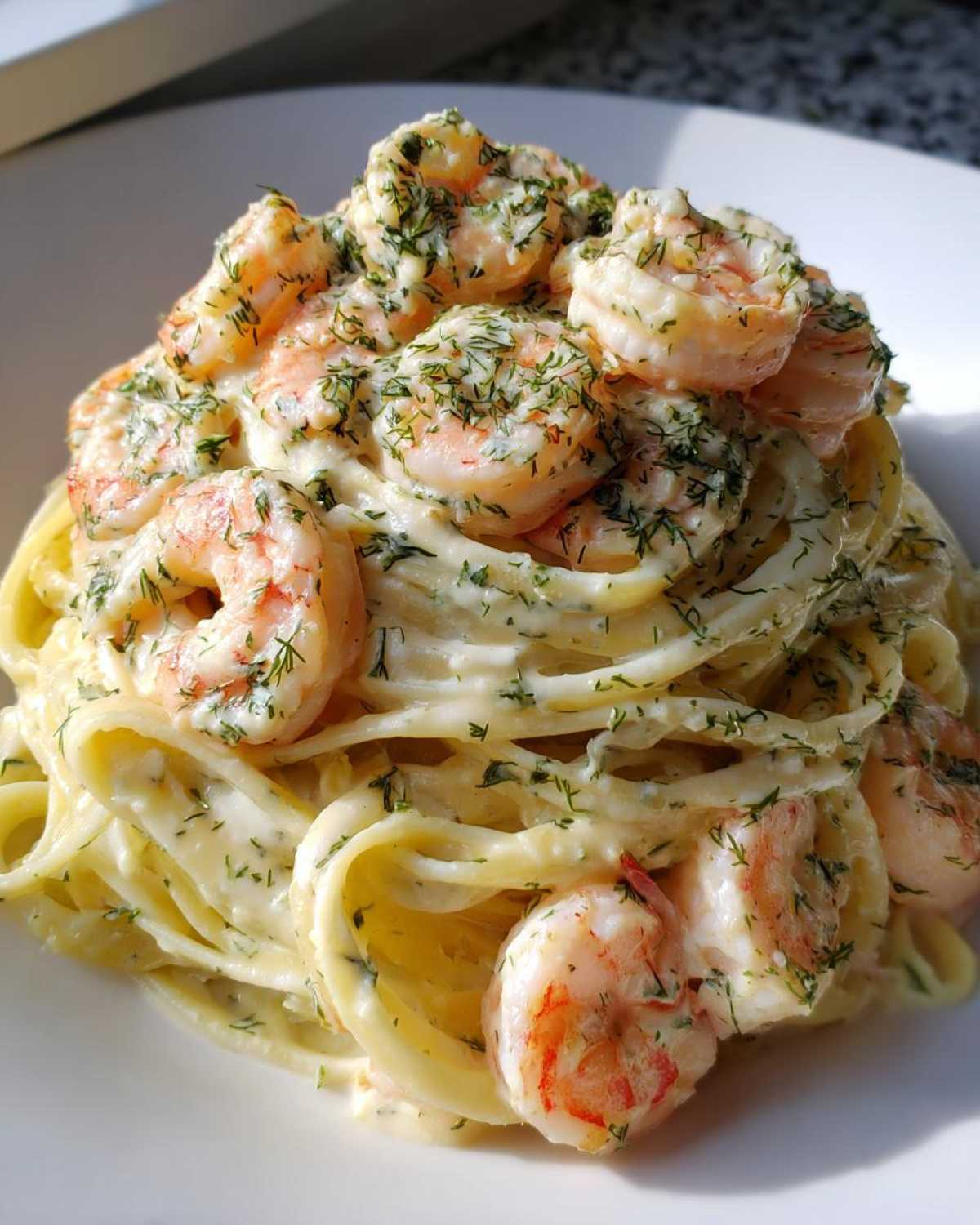 A close-up of perfectly twirled Creamy Lemon Garlic Shrimp Pasta topped with succulent shrimp and fresh dill.