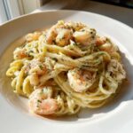 Close-up of a white bowl filled with Creamy Lemon Garlic Shrimp Pasta, topped with pink shrimp and fresh dill.