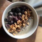 Overhead view of a Creamy Vanilla Protein Smoothie Bowl topped with blackberries, granola, and chia seeds.