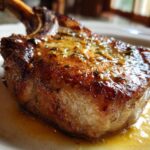 Close-up of a thick, bone-in Crispy Air Fryer Pork Chop glistening with garlic butter sauce.