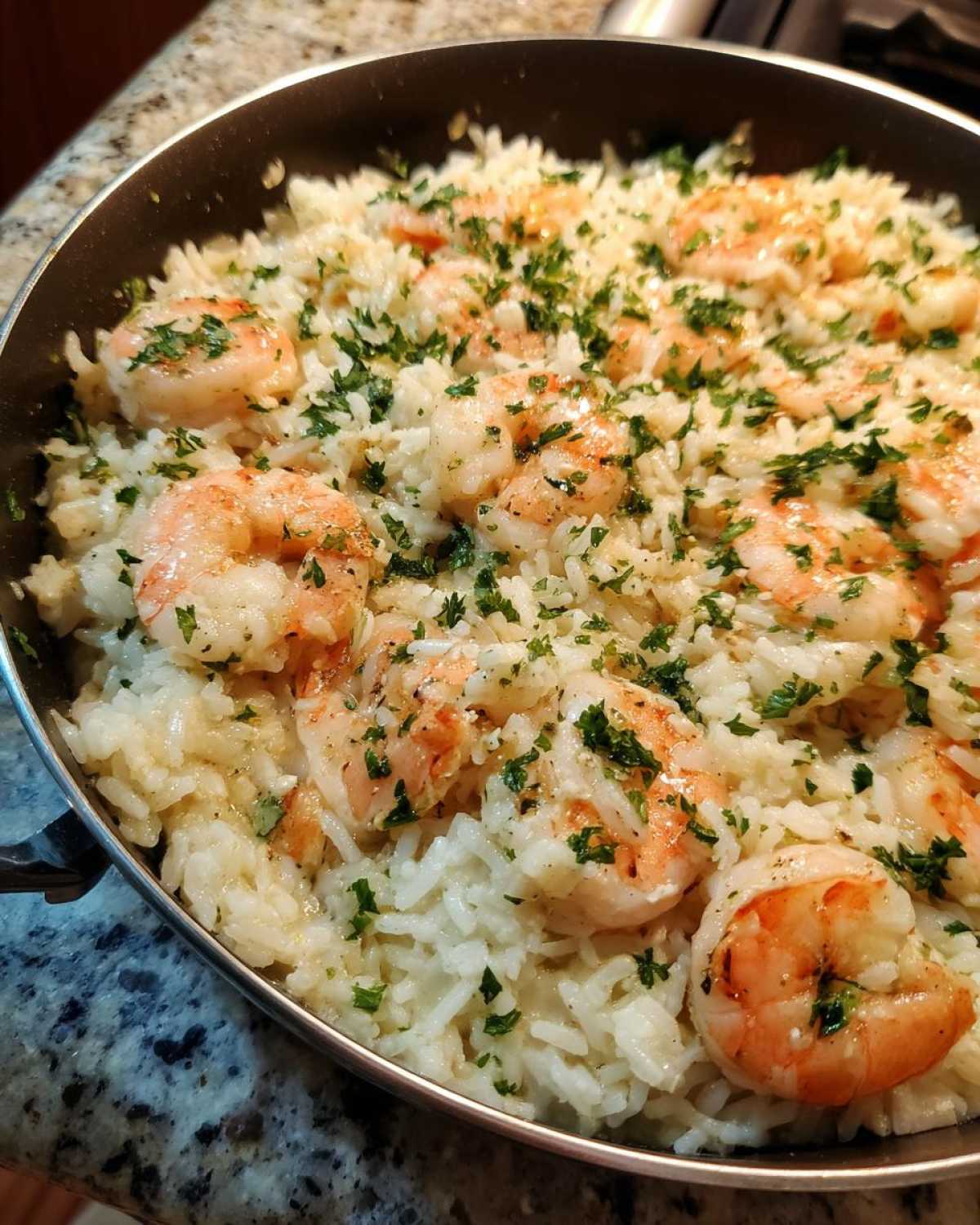 Close-up of Garlic Butter Shrimp and Rice Skillet topped with fresh parsley in a dark pan.
