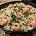 Close-up of Garlic Butter Shrimp and Rice Skillet topped with fresh parsley in a dark bowl.