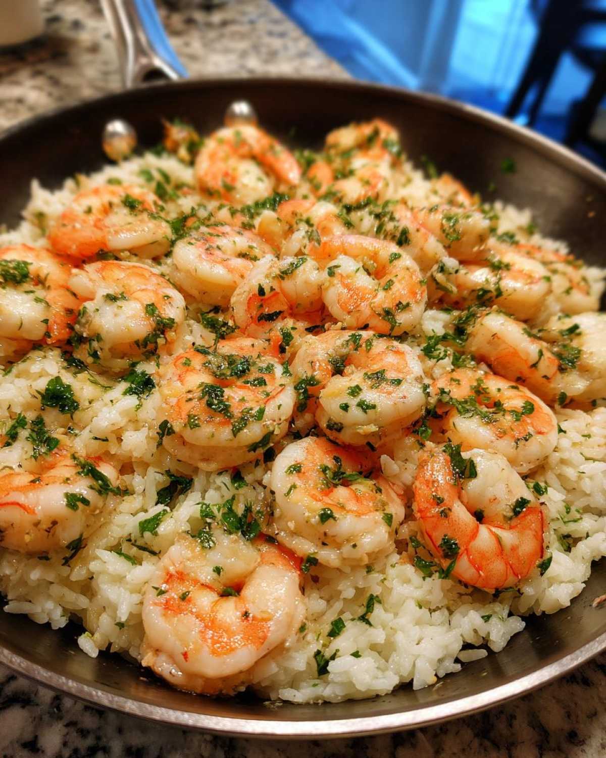 Close-up of Garlic Butter Shrimp and Rice Skillet topped with fresh parsley in a dark pan.