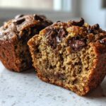 Close-up of a Gluten-Free Banana Chocolate Chip Muffin cut in half showing moist texture and melted chocolate chips.