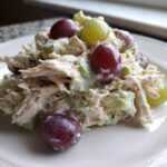 A close-up serving of creamy Honey Mustard Chicken Salad with Grapes and celery on a white plate.