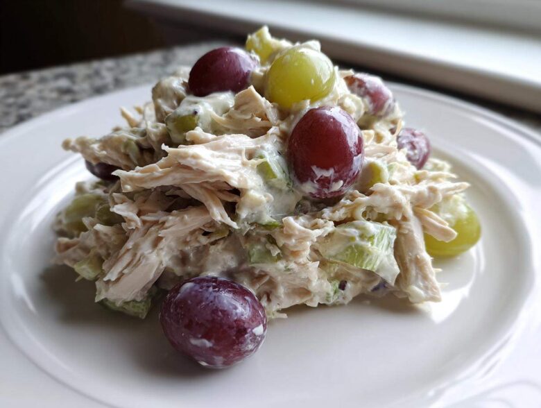 A close-up serving of creamy Honey Mustard Chicken Salad with Grapes and celery on a white plate.