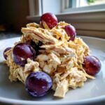 A mound of creamy Honey Mustard Chicken Salad with Grapes served on a white plate.