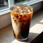 Close-up of an Iced Brown Sugar Oatmilk Latte showing rich swirls of white oatmilk mixing with dark espresso.