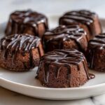 Close-up of several rich, dark chocolate Keto Chocolate Peanut Butter Fat Bombs drizzled with glossy chocolate ganache.