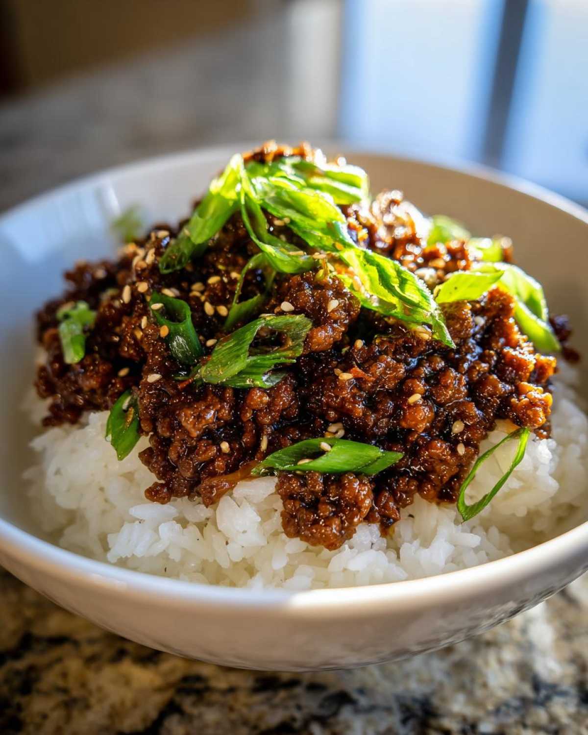 Close-up of Korean Ground Beef Bulgogi Bowls featuring savory ground beef over white rice, garnished with sesame seeds and fresh green onions.