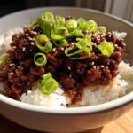 Close-up of Korean Ground Beef Bulgogi Bowls featuring rich, dark ground beef over white rice, topped with sliced green onions and sesame seeds.