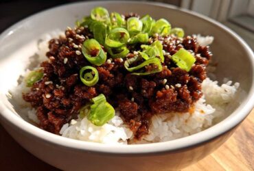 Close-up of Korean Ground Beef Bulgogi Bowls featuring rich, dark ground beef over white rice, topped with sliced green onions and sesame seeds.