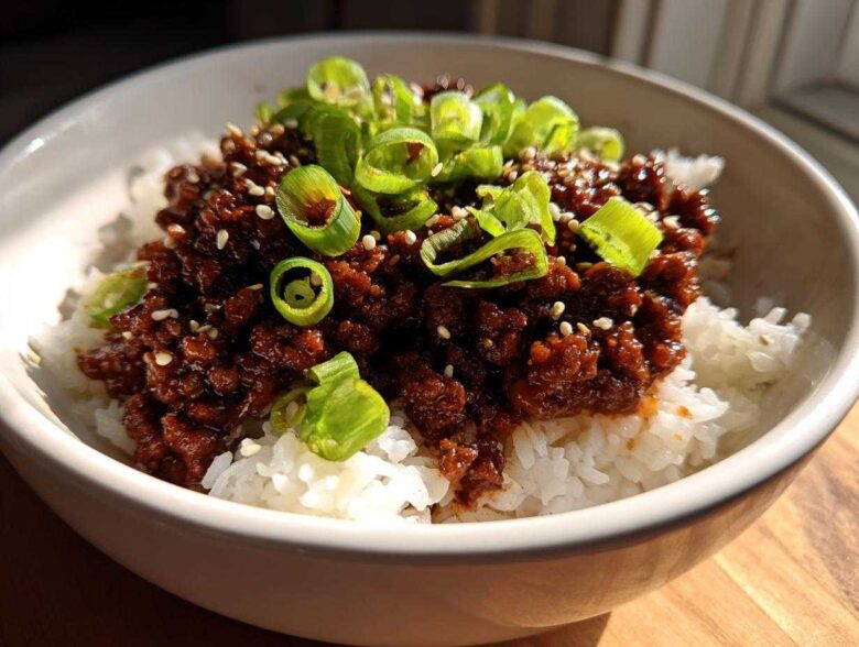 Close-up of Korean Ground Beef Bulgogi Bowls featuring rich, dark ground beef over white rice, topped with sliced green onions and sesame seeds.