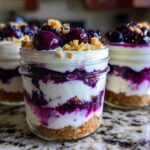 Close-up of layered Lemon Blueberry Cheesecake Jars with graham cracker crust and blueberry topping.
