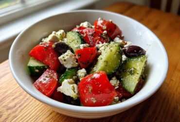Close-up of a vibrant Mediterranean Cucumber Tomato Salad with feta cheese and olives, glistening with dressing.