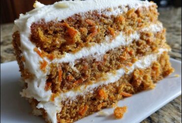 Close-up of a thick slice of Moist Carrot Cake with Cream Cheese Frosting showing two layers of cake and frosting.