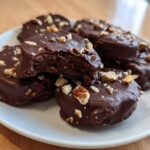 A close-up of several No-Bake Chocolate Covered Banana Bites covered in dark chocolate and sprinkled with chopped nuts.
