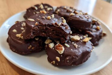 A close-up of several No-Bake Chocolate Covered Banana Bites covered in dark chocolate and sprinkled with chopped nuts.