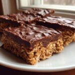 Close-up of several No-Bake Chocolate Peanut Butter Oat Bars stacked slightly on a white plate.