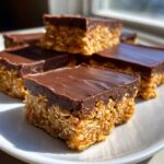 Close-up of several No-Bake Chocolate Peanut Butter Oat Bars stacked on a white plate.